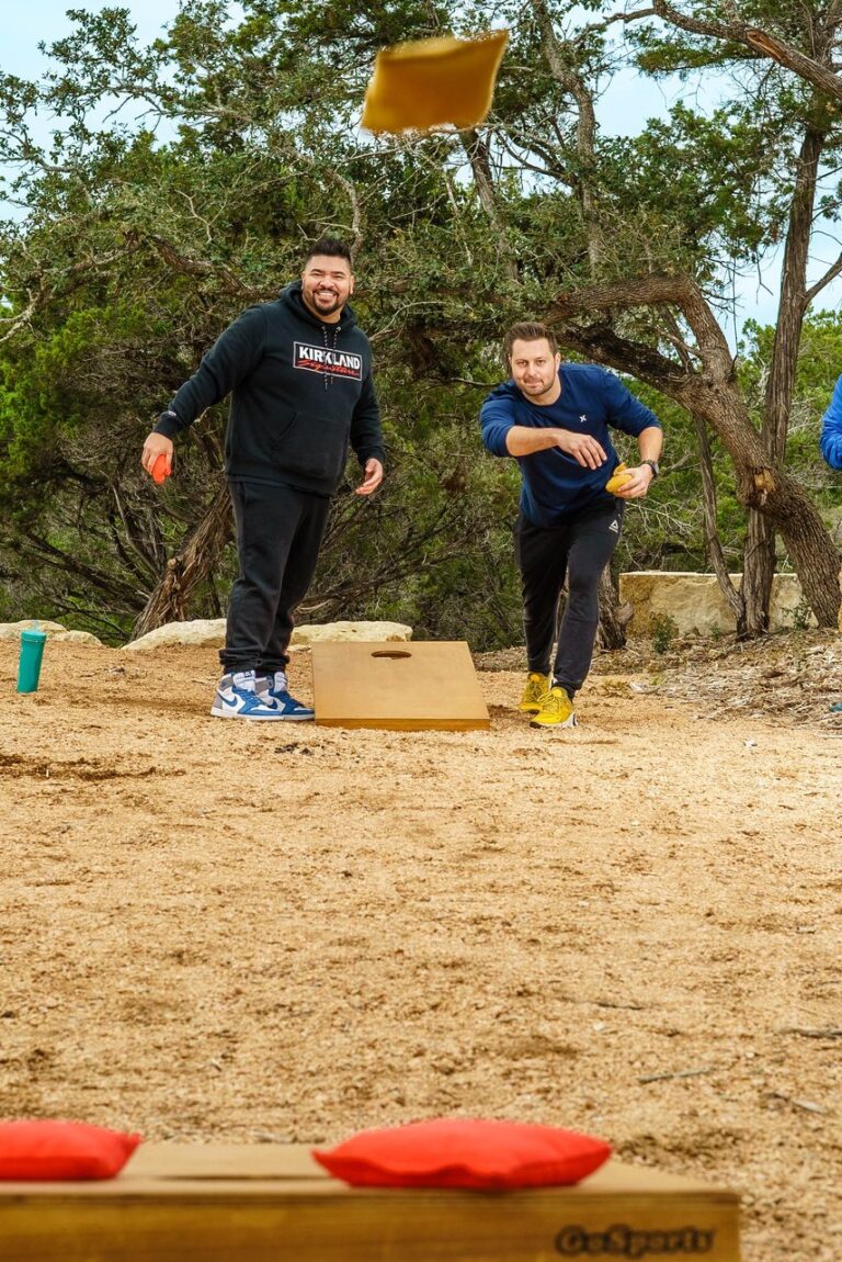 Two guests playing cornhole outdoors at Starlight Horizon, tossing bean bags toward a wooden board
