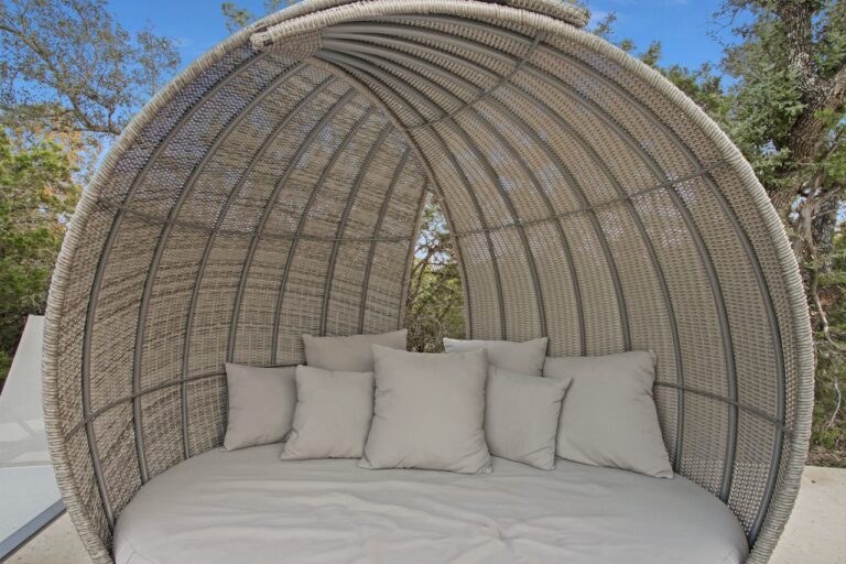 Close-up of a curved wicker daybed lounge chair with cushions near the pool