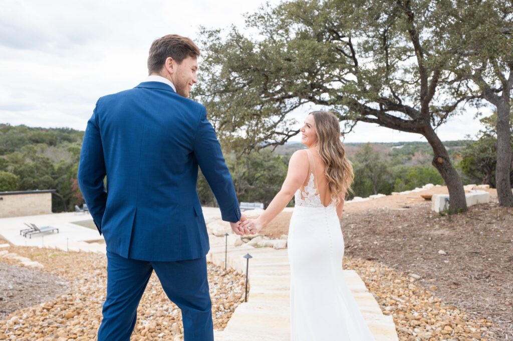 Bride and groom walking hand in hand toward the pool at Starlight Horizon, a boutique cabin resort near Canyon Lake, Texas