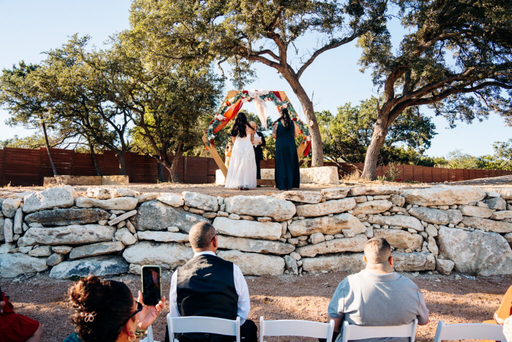 October wedding ceremony beneath the floral arch at Starlight Horizon, a boutique cabin resort near Canyon Lake, Texas