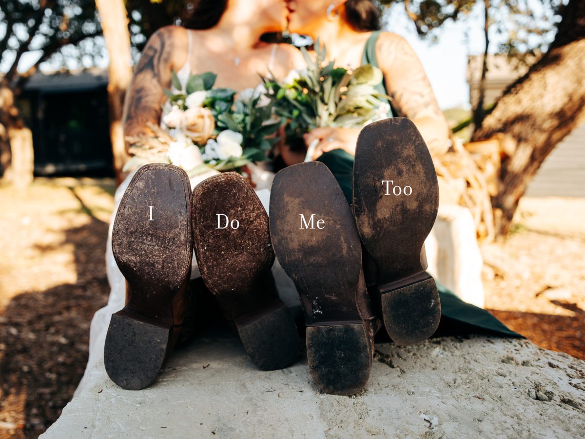 Newlywed couple kissing with "I Do Me Too" boot soles at Starlight Horizon, a boutique cabin resort near Canyon Lake, Texas
