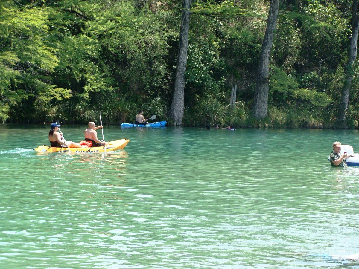 Kayakers paddling the clear green Frio River at Garner State Park in the Texas Hill Country