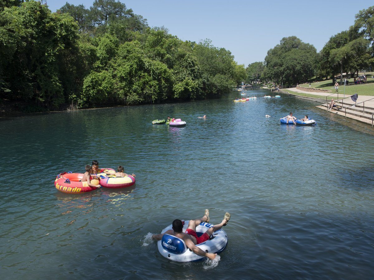Tubers drifting down the clear Comal River channel at Prince Solms Park in New Braunfels Texas